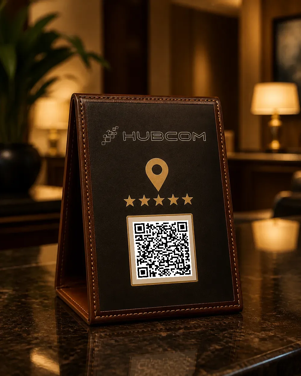 Standee bọc da bò nâu khâu chỉ nổi dựng trên quầy lễ tân đá đen, mặt trước in logo Hubcom, ghim bản đồ vàng, năm ngôi sao và mã QR quét được dẫn tới trang đánh giá